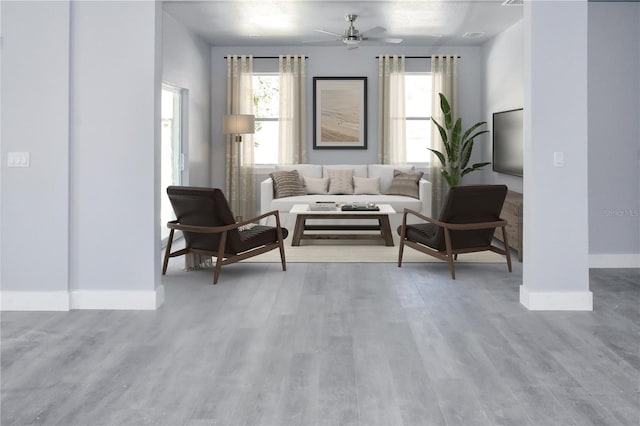 living room featuring a ceiling fan, baseboards, and wood finished floors