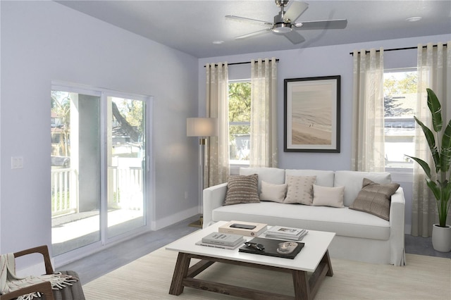 living room featuring baseboards, plenty of natural light, and a ceiling fan