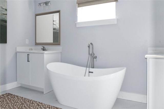 full bath with a freestanding tub, baseboards, marble finish floor, and vanity