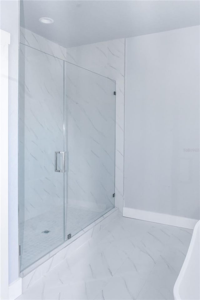 full bath with a marble finish shower, baseboards, and marble finish floor