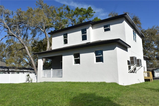 rear view of house featuring a yard, stucco siding, and fence