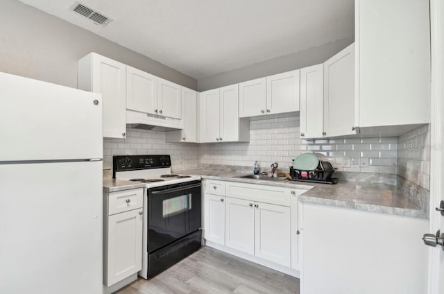 kitchen featuring visible vents, electric stove, under cabinet range hood, a sink, and freestanding refrigerator