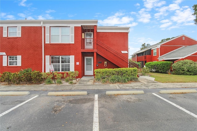 view of property with stairs and uncovered parking