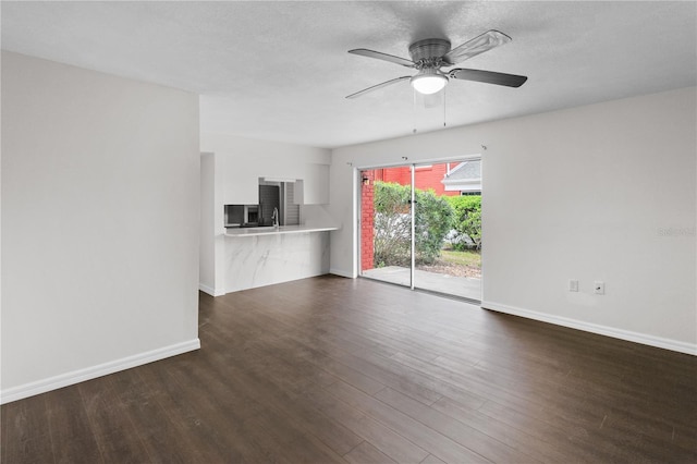 unfurnished living room with a textured ceiling, a ceiling fan, baseboards, and wood finished floors