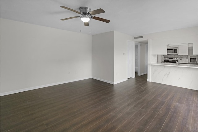 unfurnished living room featuring baseboards, visible vents, dark wood-style flooring, a sink, and ceiling fan