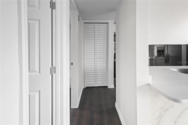 hall with a sink, baseboards, and dark wood-type flooring