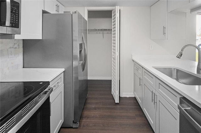 kitchen featuring a sink, light stone counters, dark wood-style floors, white cabinetry, and appliances with stainless steel finishes