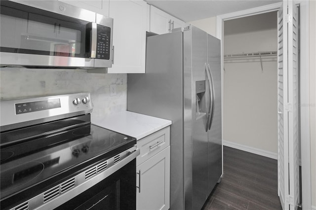 kitchen with light stone countertops, dark wood-style flooring, stainless steel appliances, white cabinets, and tasteful backsplash