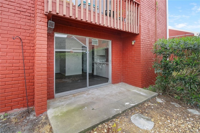 property entrance with brick siding and a balcony