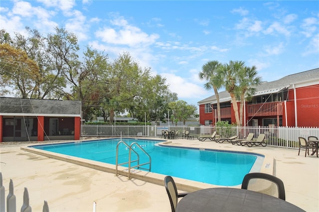 community pool with a patio area and fence