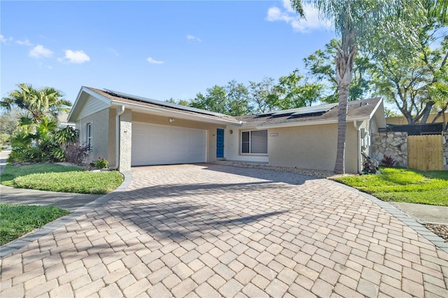 12605 Catamaran Pl, Tampa, FL 33618 - view of front of property with stucco siding, decorative driveway, roof mounted solar panels, fence, and a garage