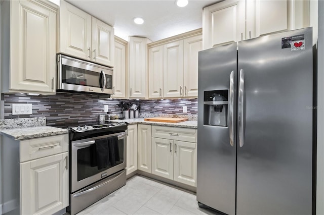 kitchen featuring light stone counters, light tile patterned floors, backsplash, and stainless steel appliances