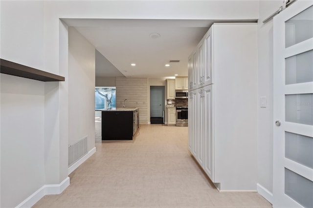 corridor featuring visible vents, recessed lighting, baseboards, and a sink