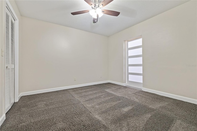 unfurnished bedroom with dark colored carpet, baseboards, a closet, and ceiling fan