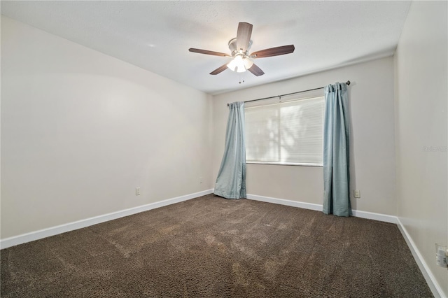 spare room featuring dark carpet, baseboards, and ceiling fan