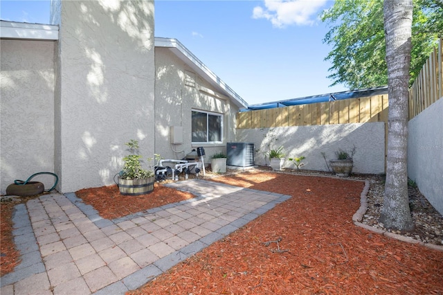 exterior space with a patio area, a fenced backyard, and central AC