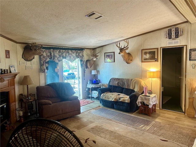 living area featuring crown molding, wood finished floors, visible vents, and a textured ceiling