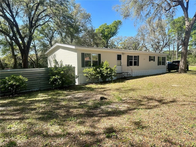 rear view of property featuring a lawn and entry steps