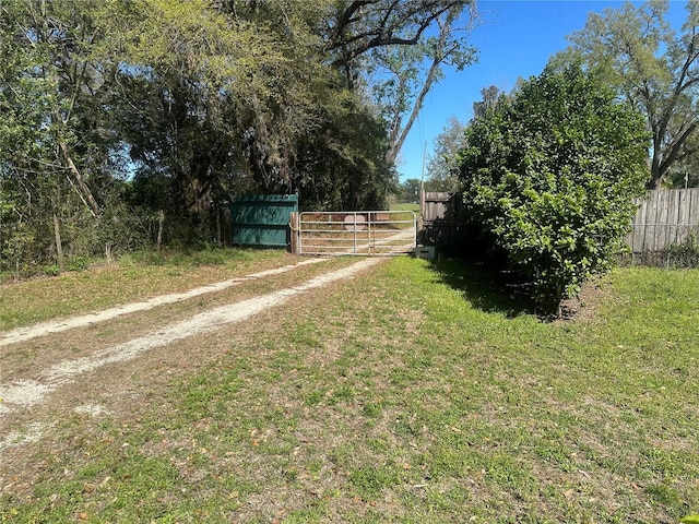 view of yard featuring fence and dirt driveway