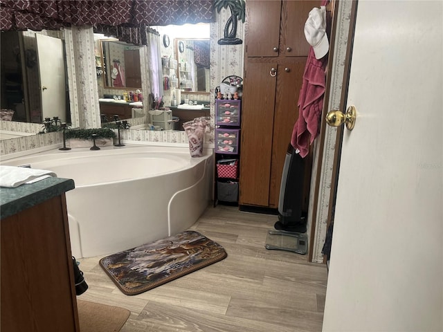 bathroom featuring wood finished floors, vanity, and wallpapered walls