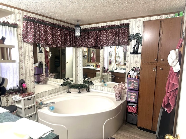 full bathroom featuring a bath, a textured ceiling, wallpapered walls, and wood finished floors