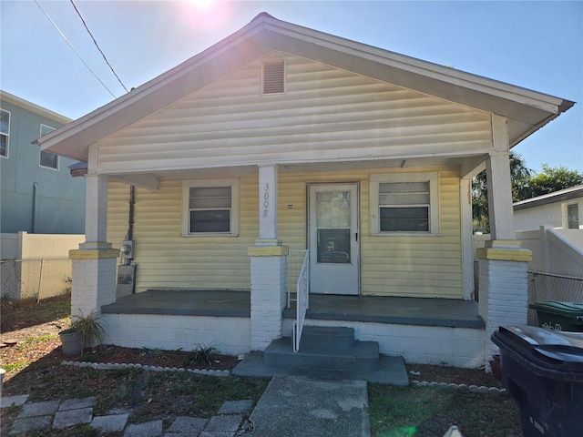 view of front of home featuring covered porch and fence