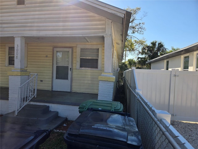 entrance to property with a porch and fence