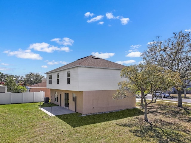 rear view of house featuring fence, central air condition unit, a lawn, stucco siding, and a patio area