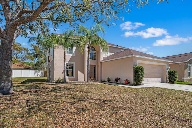 view of front facade featuring a front lawn, fence, stucco siding, a garage, and driveway