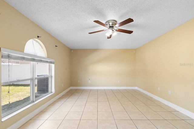 empty room with a ceiling fan, baseboards, lofted ceiling, light tile patterned flooring, and a textured ceiling