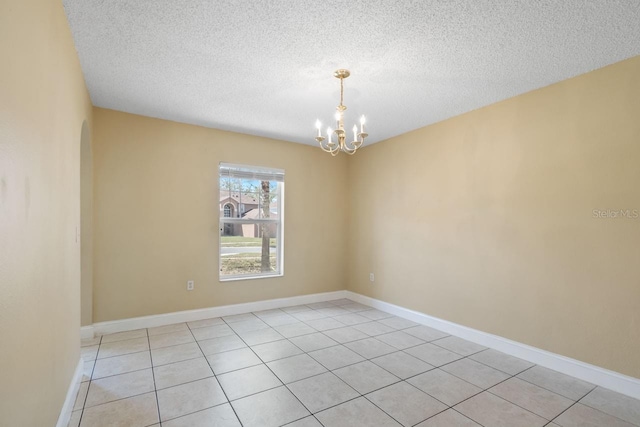 spare room with a chandelier, a textured ceiling, and baseboards