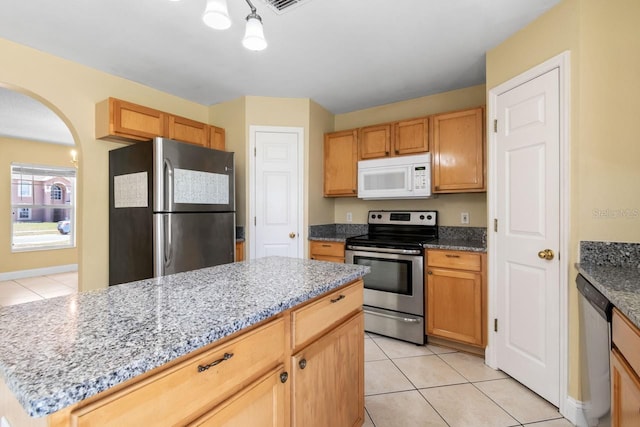 kitchen featuring arched walkways, light tile patterned floors, stainless steel appliances, and light stone countertops