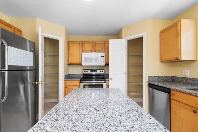 kitchen featuring stainless steel appliances, light stone countertops, and light tile patterned flooring