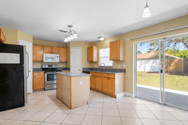 kitchen with visible vents, a kitchen island, appliances with stainless steel finishes, light tile patterned flooring, and a sink