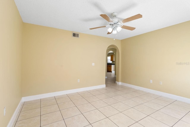 spare room featuring baseboards, visible vents, arched walkways, ceiling fan, and a textured ceiling