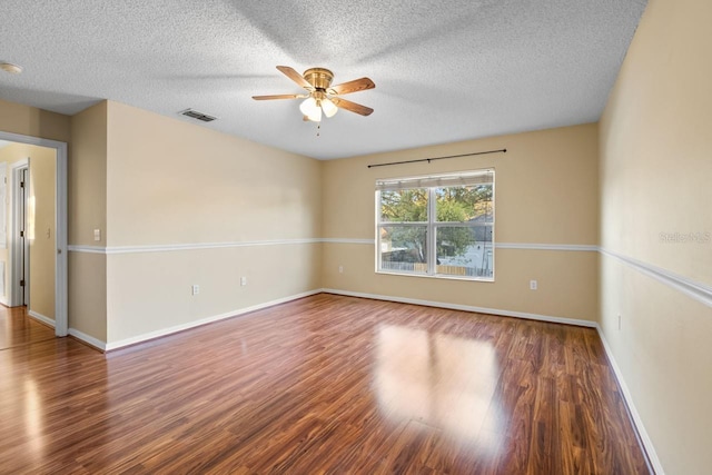 empty room featuring wood finished floors, a ceiling fan, visible vents, and baseboards