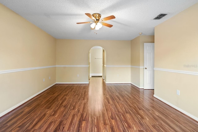 unfurnished room with wood finished floors, arched walkways, visible vents, and ceiling fan