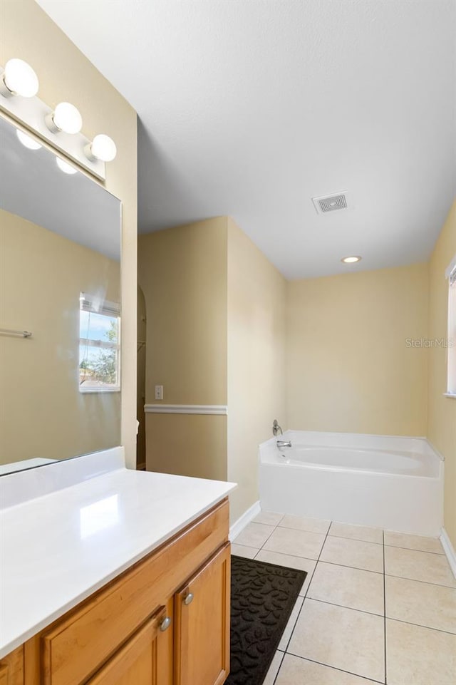 bathroom featuring vanity, visible vents, baseboards, tile patterned flooring, and a bath