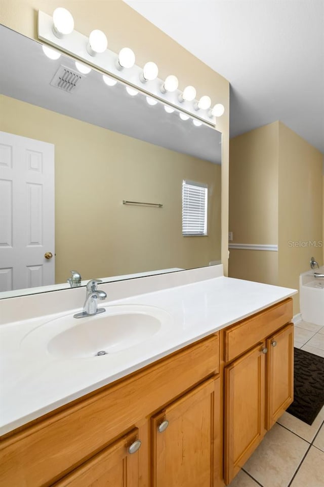 bathroom featuring tile patterned floors, visible vents, a bath, and vanity