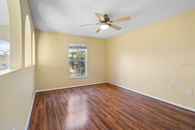 empty room featuring baseboards, a textured ceiling, wood finished floors, and a ceiling fan