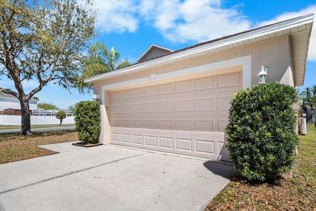 garage featuring driveway and fence