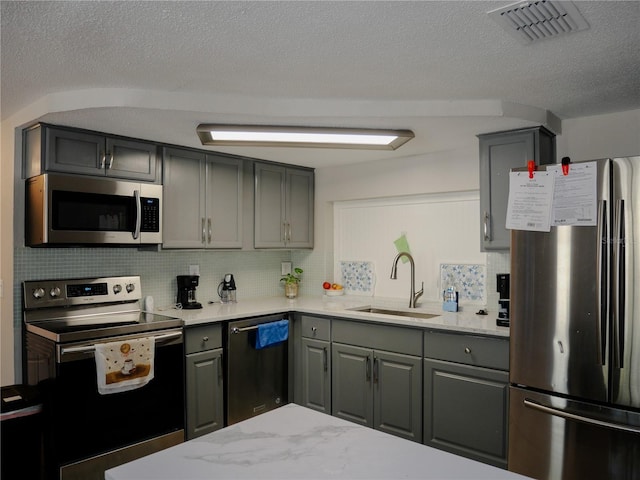 kitchen featuring visible vents, gray cabinets, a sink, stainless steel appliances, and backsplash