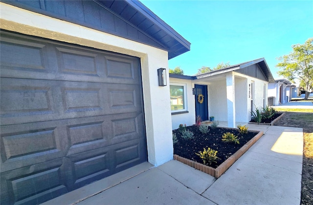 view of exterior entry featuring stucco siding and a garage