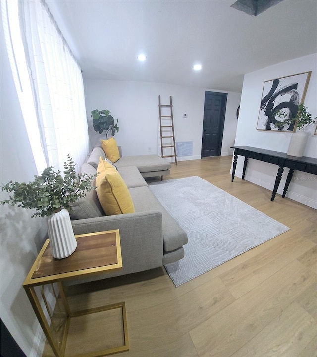 living room with recessed lighting, visible vents, baseboards, and wood finished floors