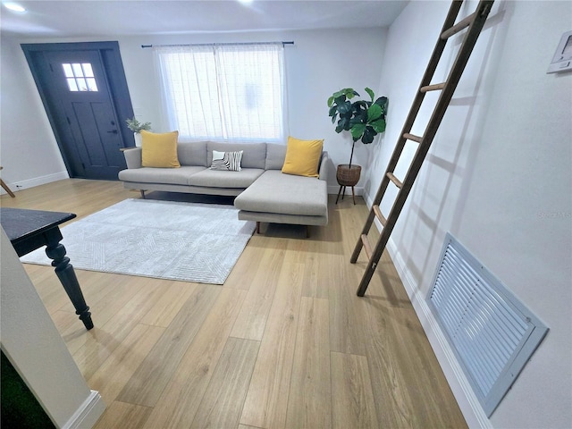 living room with visible vents, baseboards, and light wood-style floors