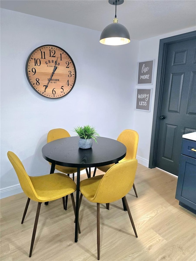 dining area with baseboards and light wood-style flooring