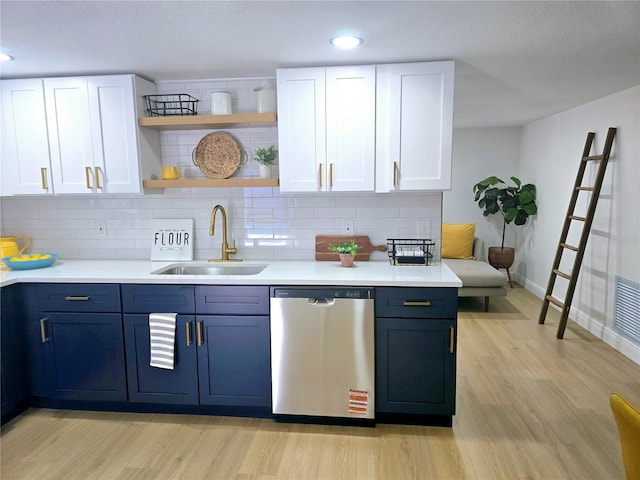 kitchen with a sink, open shelves, stainless steel dishwasher, white cabinets, and light countertops