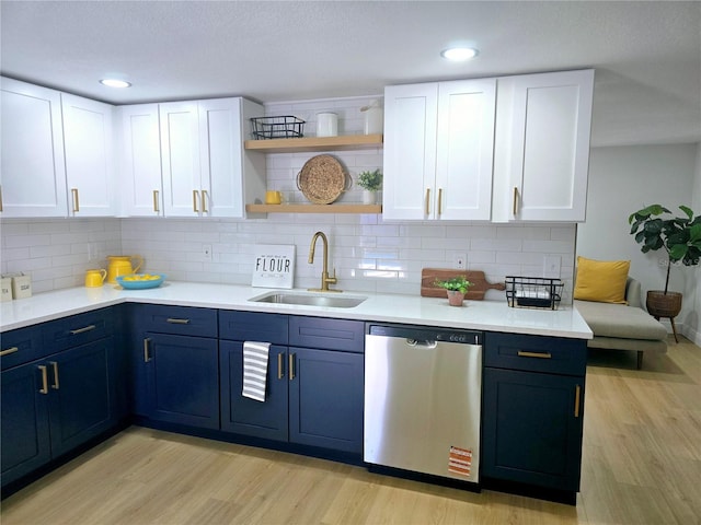 kitchen featuring a sink, blue cabinetry, stainless steel dishwasher, and light wood finished floors