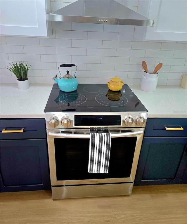 kitchen with backsplash, blue cabinetry, extractor fan, and stainless steel range with electric cooktop