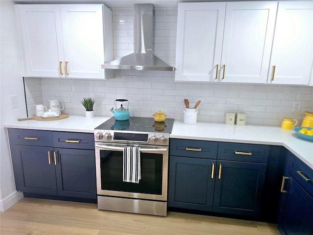 kitchen with light wood-style flooring, stainless steel range with electric cooktop, white cabinets, wall chimney exhaust hood, and backsplash